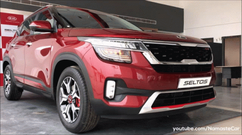 A Red Kia Seltos Is On Display At A Kia Dealership GIF