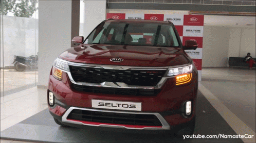 A Red Kia Seltos Is On Display At A Kia Dealership GIF