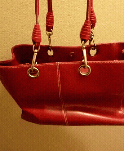 A Red Leather Purse With Two Handles Is Hanging From A Wall GIF