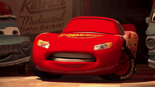 A Red Lightning Mcqueen Car Is Standing In Front Of A Rusteze Medicated Bumper Ointment Sign GIF