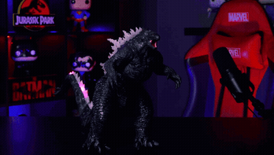A Red Marvel Chair Sits In Front Of A Glowing Godzilla Figure GIF