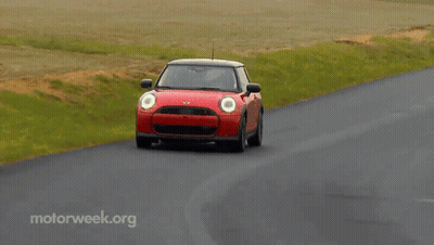 A Red Mini Cooper Is Driving Down A Curvy Road With Motorweek.org Written On The Bottom GIF