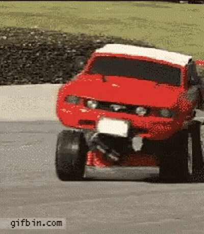 A Red Monster Truck Is Driving Down A Road With A Gifbin.com Watermark At The Bottom GIF