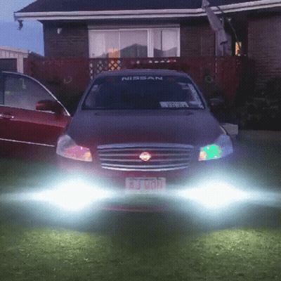 A Red Nissan Car Is Parked In Front Of A Brick House GIF