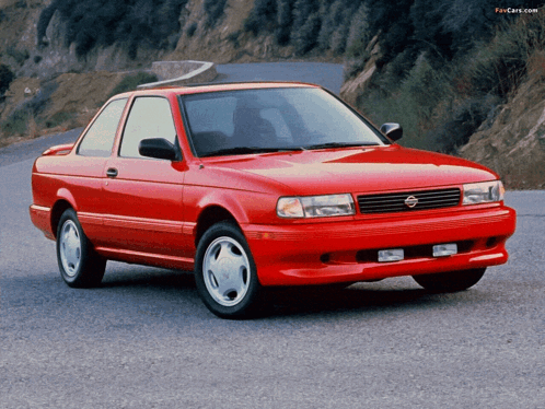 A Red Nissan Is Parked On The Side Of A Road GIF