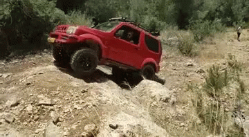 A Red Off Road Vehicle Is Driving Down A Rocky Hill . GIF