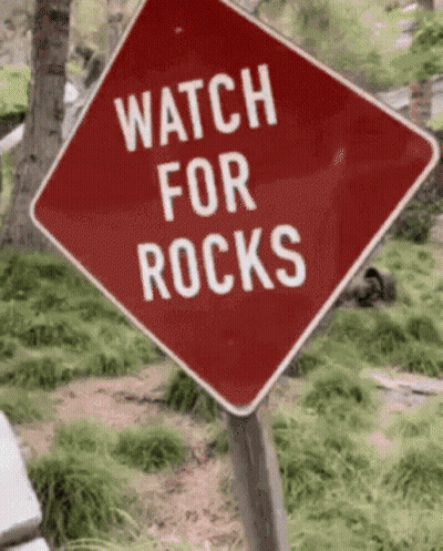 A Red Sign That Says Watch For Rocks GIF