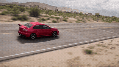 A Red Sports Car Is Driving Down A Desert Road GIF