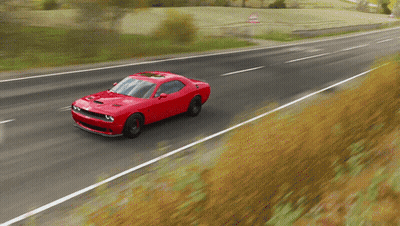 A Red Sports Car Is Driving Down A Road GIF