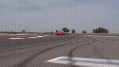 A Red Sports Car Is Driving Down A Road GIF