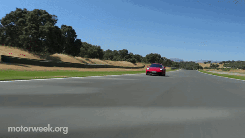 A Red Sports Car Is Driving Down A Road With Motorweek.org Written On The Bottom Right GIF