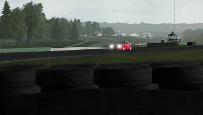 A Red Sports Car Is Driving Down A Track With Tires In The Foreground GIF