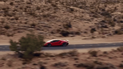 A Red Sports Car Is Driving On A Desert Road GIF