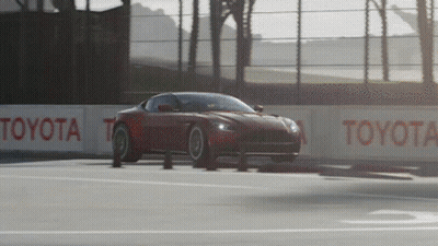 A Red Sports Car Is Driving On A Race Track With Toyota Signs Along The Side GIF