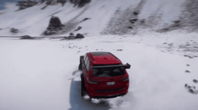 A Red Suv Is Driving Through The Snow On A Mountain GIF