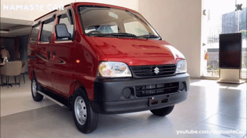 A Red Suzuki Van Is Displayed In A Showroom GIF