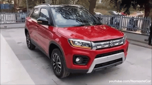 A Red Suzuki Vitara Is Parked In A Parking Lot . GIF