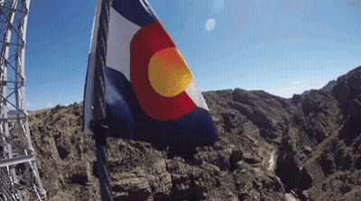 A Red White And Blue Flag With A Yellow Center Is Flying In The Wind GIF