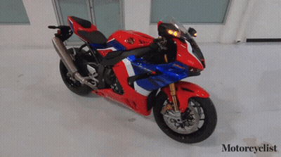 A Red White And Blue Honda Motorcycle Is Parked In A Room GIF