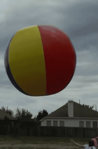 A Red Yellow And Blue Beach Ball Flies In The Air GIF