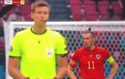 A Referee And A Soccer Player Are Standing Next To Each Other . GIF