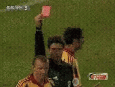 A Referee Holds Up A Red Card In Front Of A Player Wearing A Yellow Jersey With The Number 22 On It GIF