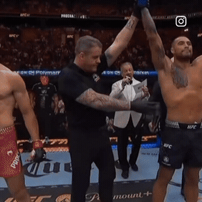 A Referee Holds Up A Shirtless Fighter 'S Arm In A Boxing Ring GIF