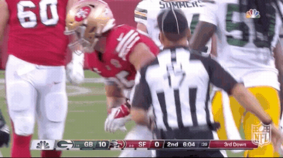 A Referee Is Standing In Front Of A Football Player During A Game . GIF