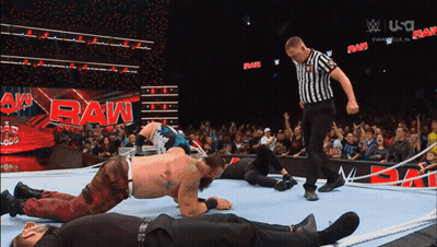 A Referee Is Standing In Front Of A Raw Sign GIF
