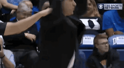 A Referee Is Standing In The Stands During A Basketball Game And Talking To A Player . GIF