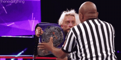 A Referee Is Standing Next To A Wrestler Holding A Wrestling Championship Belt . GIF