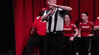 A Referee Is Standing On A Stage Talking To A Group Of People . GIF