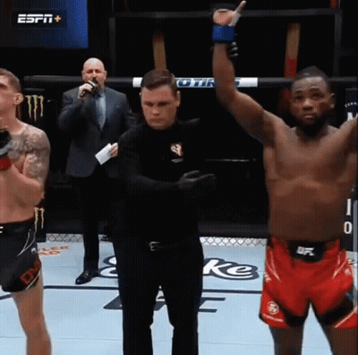A Referee Stands Between Two Fighters In A Boxing Ring While One Of Them Raises His Hand In The Air GIF