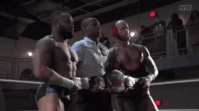 A Referee Stands Between Two Wrestlers In A Wrestling Ring With The Word Fite On The Bottom GIF