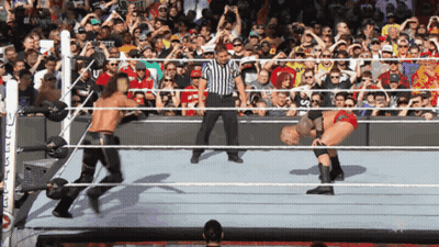 A Referee Stands In A Wrestling Ring Watching A Match GIF
