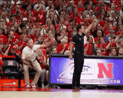 A Referee Stands In Front Of A Nebraska Banner GIF