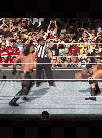 A Referee Stands In The Middle Of A Wrestling Match Between Two Men GIF