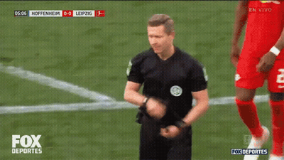 A Referee Stands On A Soccer Field With The Fox Deportes Logo On The Bottom GIF