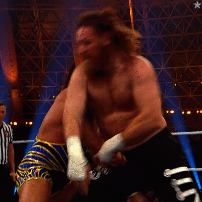 A Referee Watches Two Men Fight In A Wrestling Ring With A Sign That Says Queen On It GIF