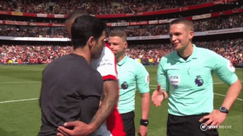 A Referee Wearing A Fifa Shirt Shakes Hands With A Player On A Soccer Field GIF