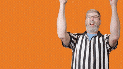 A Referee With His Arms In The Air And The Word Goal In The Background GIF