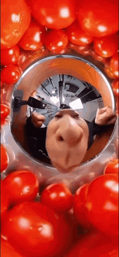 A Reflection Of A Person 'S Face In A Bowl Of Tomatoes . GIF