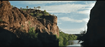 A River Runs Through A Canyon Surrounded By Trees And Rocks GIF
