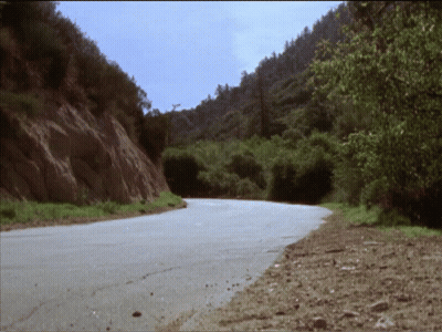 A Road That Is Going Through A Valley With Trees On Both Sides GIF