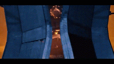 A Robot Is Standing In A Dark Room With A Blue Curtain . GIF