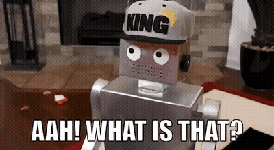 A Robot Wearing A Hat With The Word King On It Is Sitting On The Floor In A Living Room . GIF