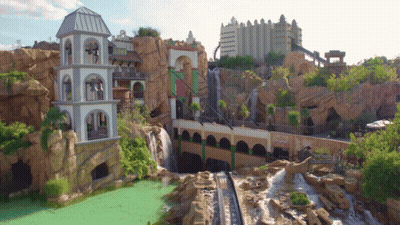 A Roller Coaster With A Waterfall In The Background And A Building That Says ' Eiffel Tower ' On The Side GIF