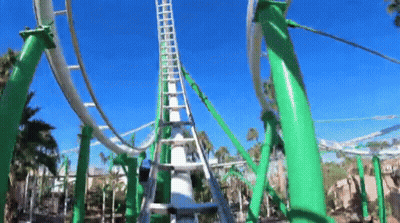 A Roller Coaster With Green Poles And A Blue Sky In The Background . GIF