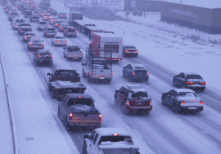 A Row Of Cars Are Driving Down A Snow Covered Highway GIF