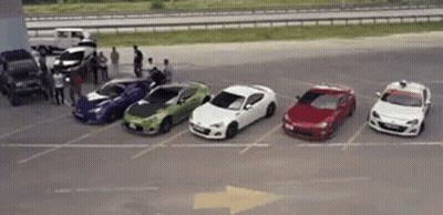 A Row Of Cars Are Parked In A Parking Lot Next To Each Other . GIF